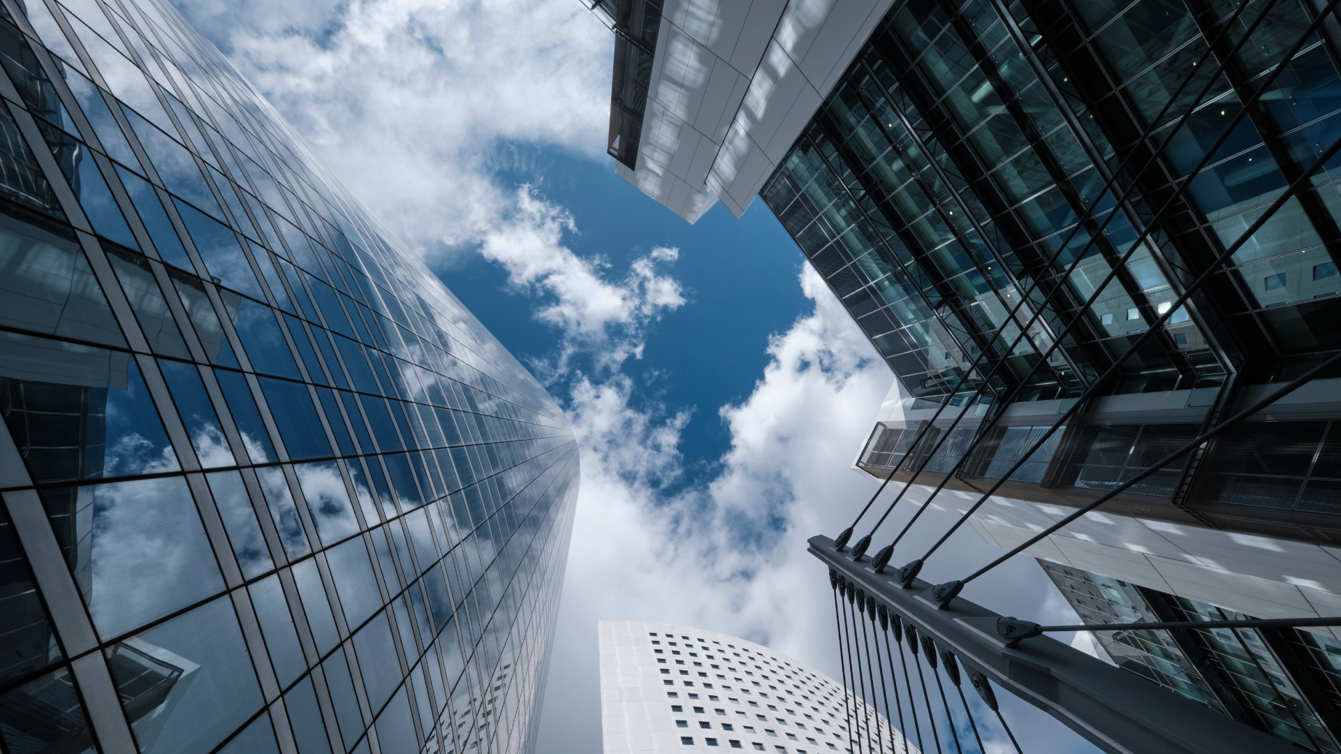 抜けるような青空と白い雲、そして光を反射する近代的なガラス張りの高層ビル群のパース写真
